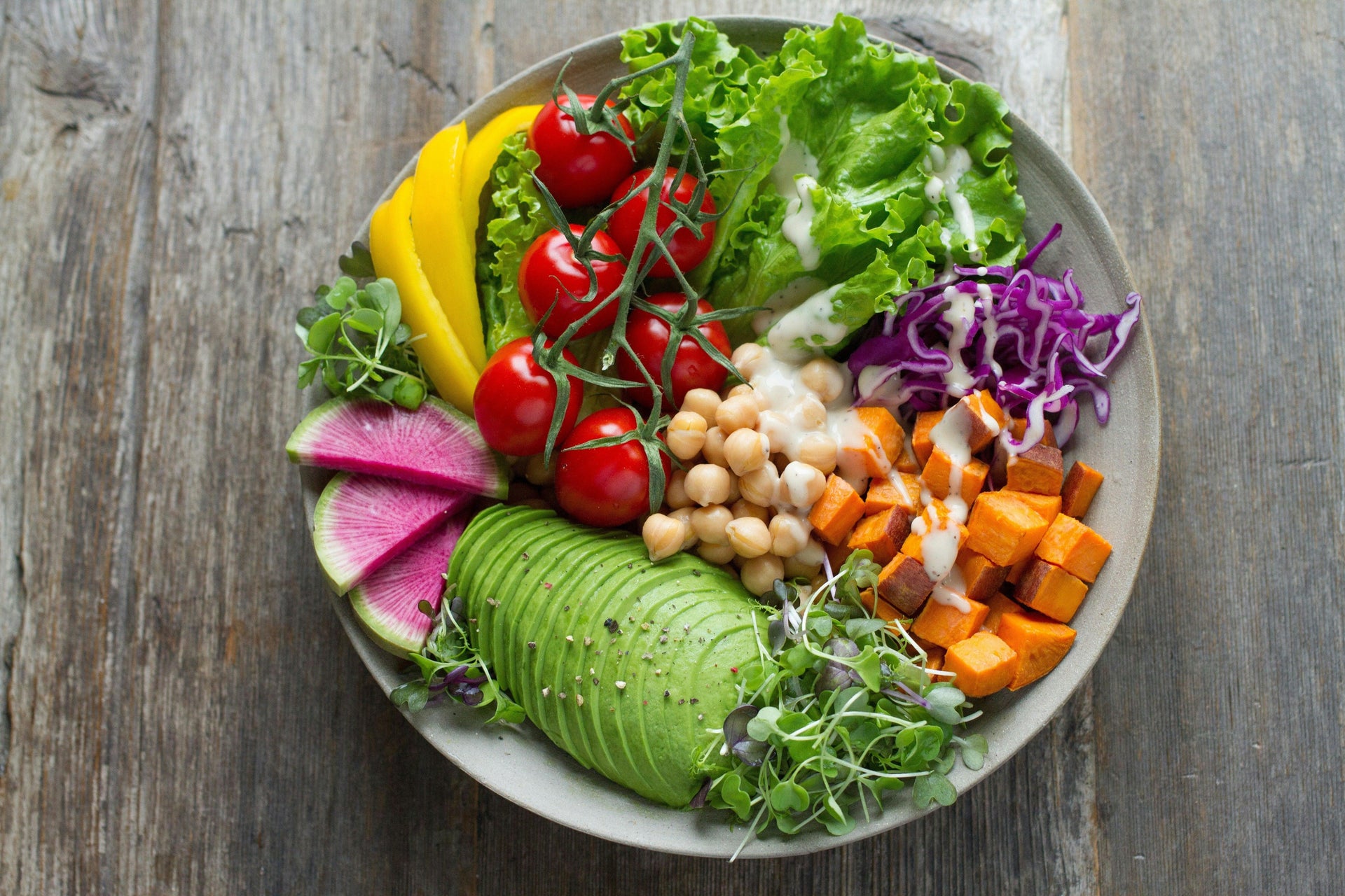 Colorful healthy salad bowl with avocado, cherry tomatoes, chickpeas, sweet potato, and greens