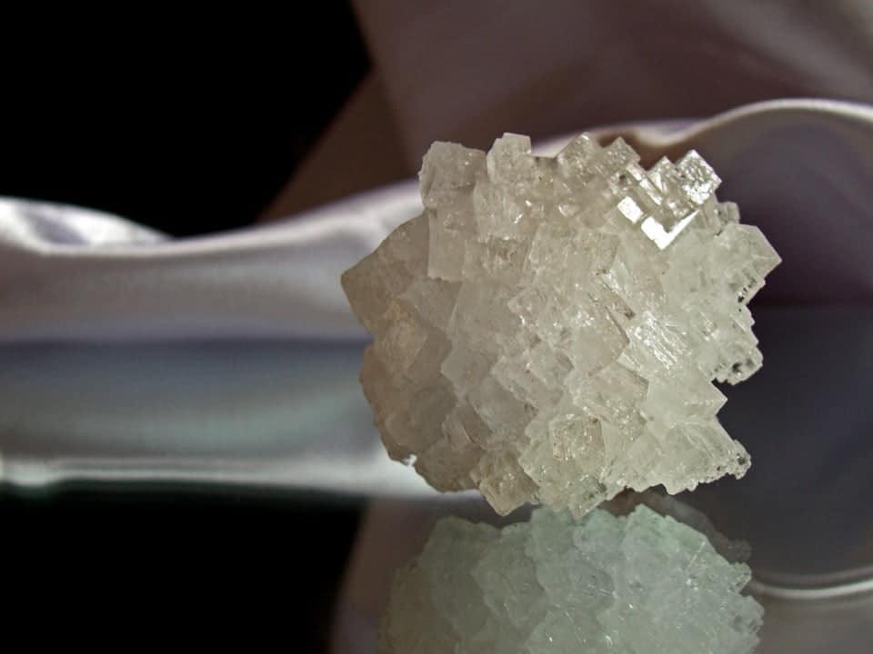 Close-up of clear iodine crystal cluster on reflective surface, Magnascent Iodine context.