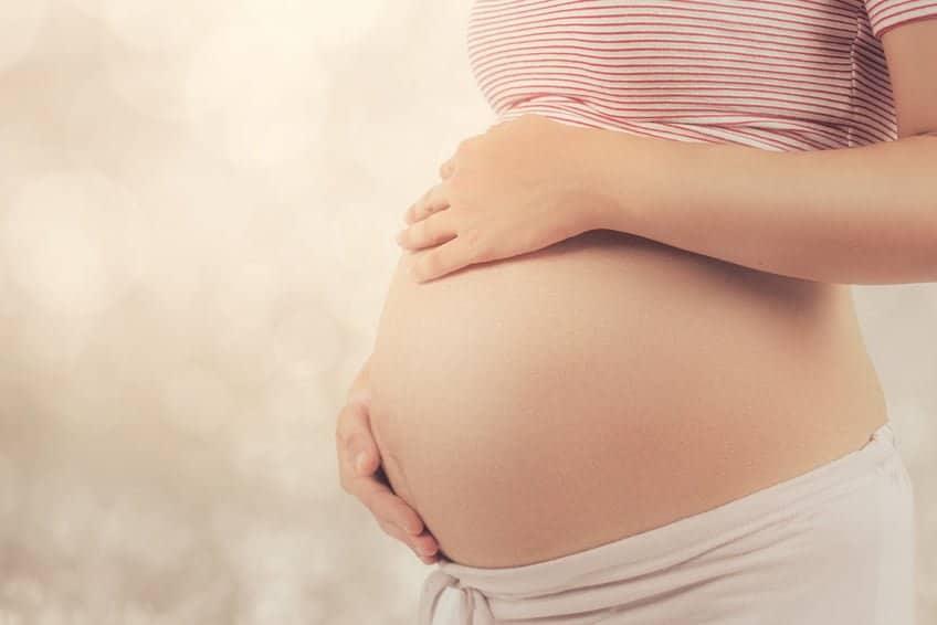 Pregnant woman holding belly, highlighting prenatal health and iodine supplement benefits